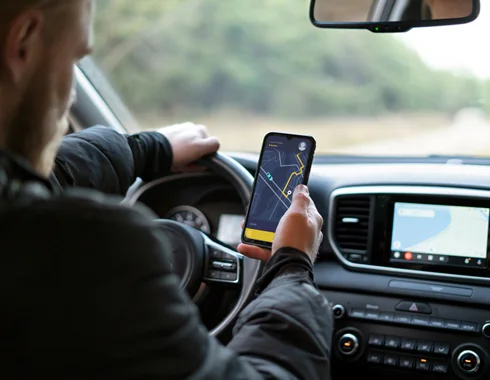 A driver stares at the directional map on his phone, while driving.