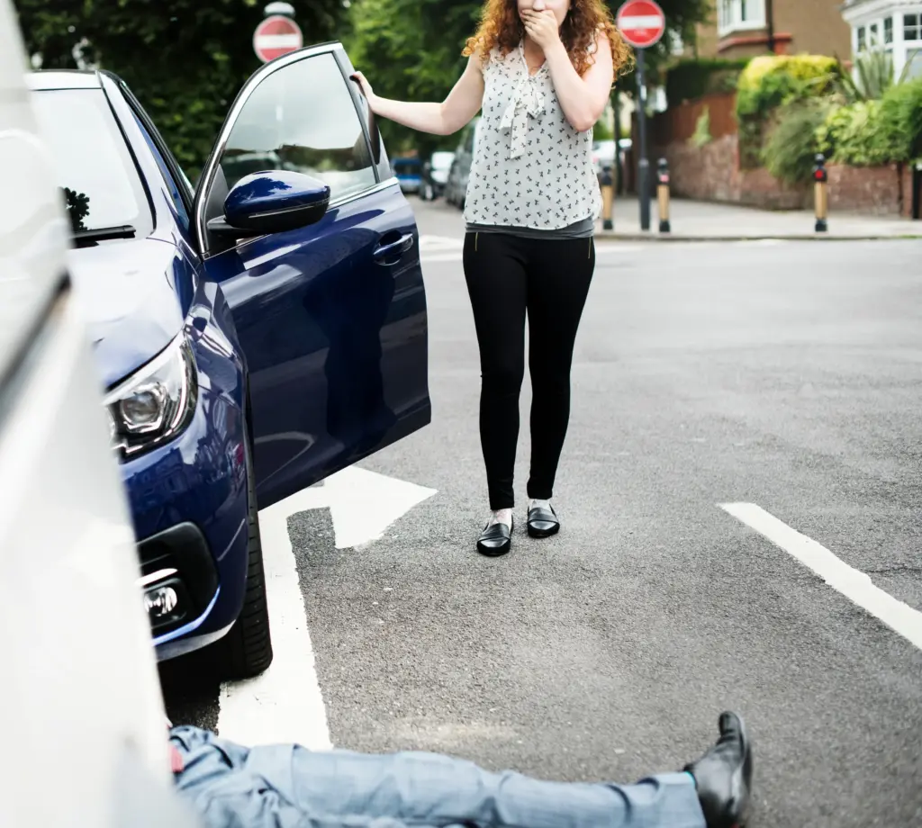 A woman standing by her car after hitting a pedestrian.