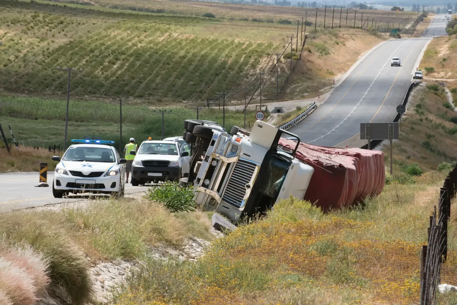 A semi rolled over on the side of a highway.