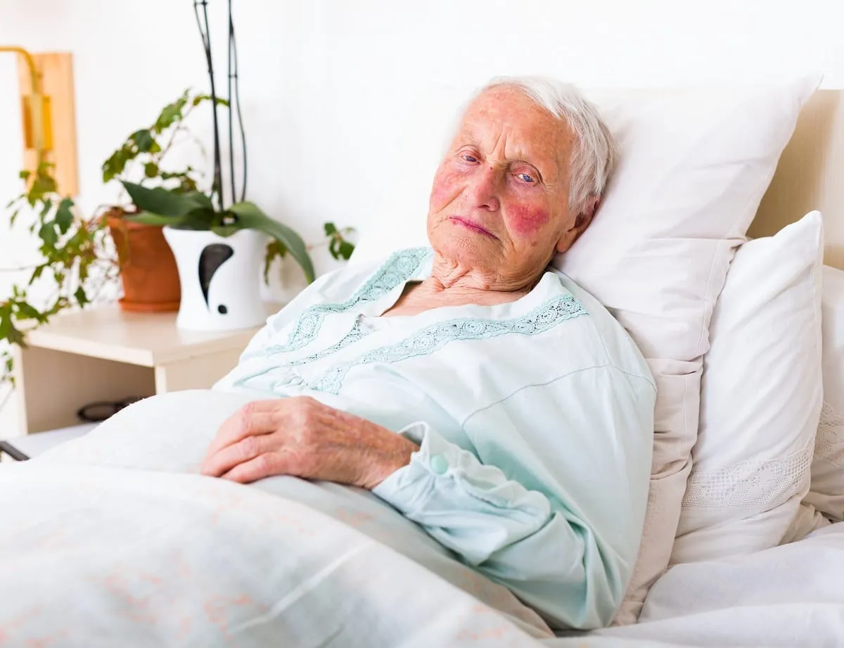 A nursing home resident laying in a bed.