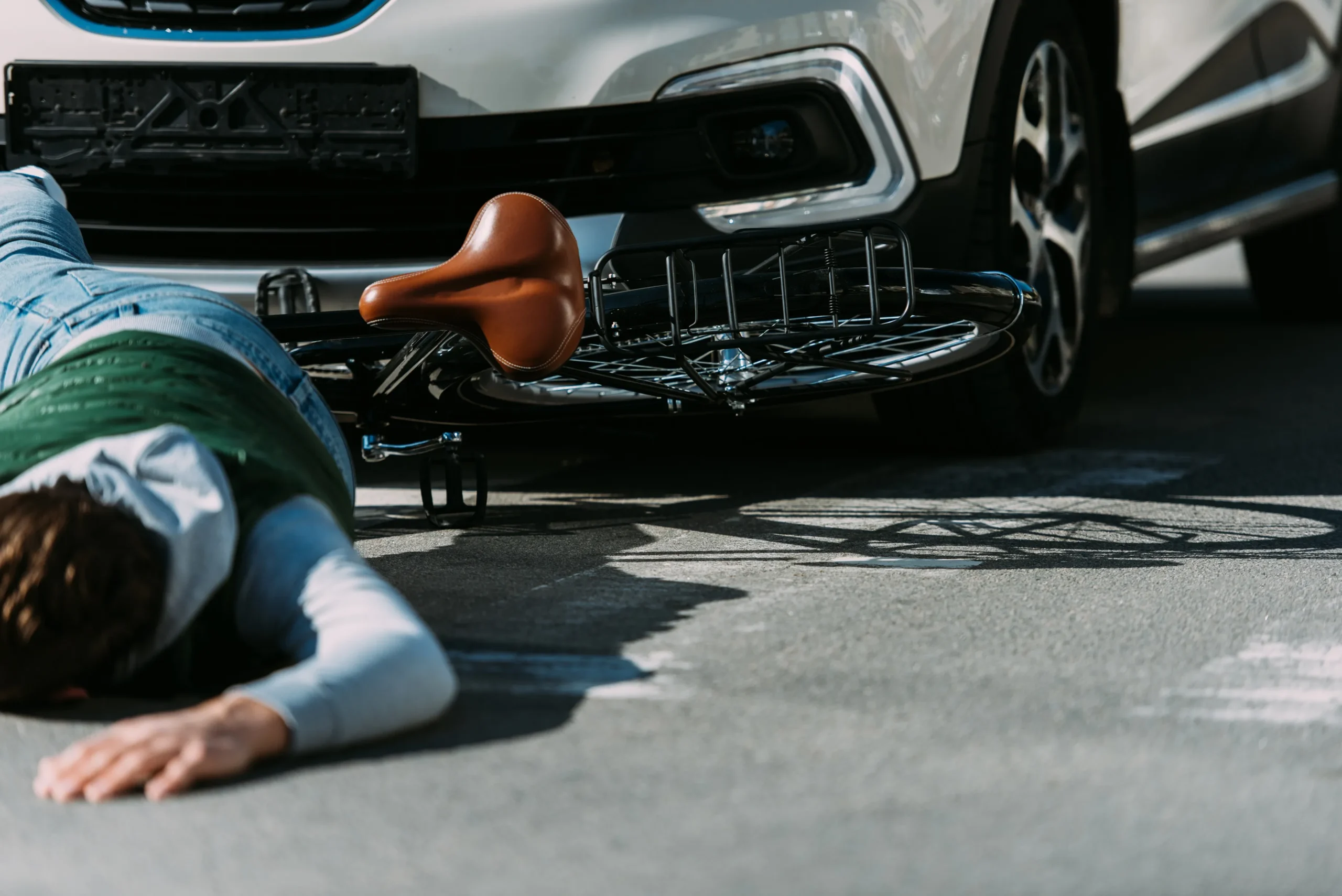 A cyclist hit by a car, laying on the ground.