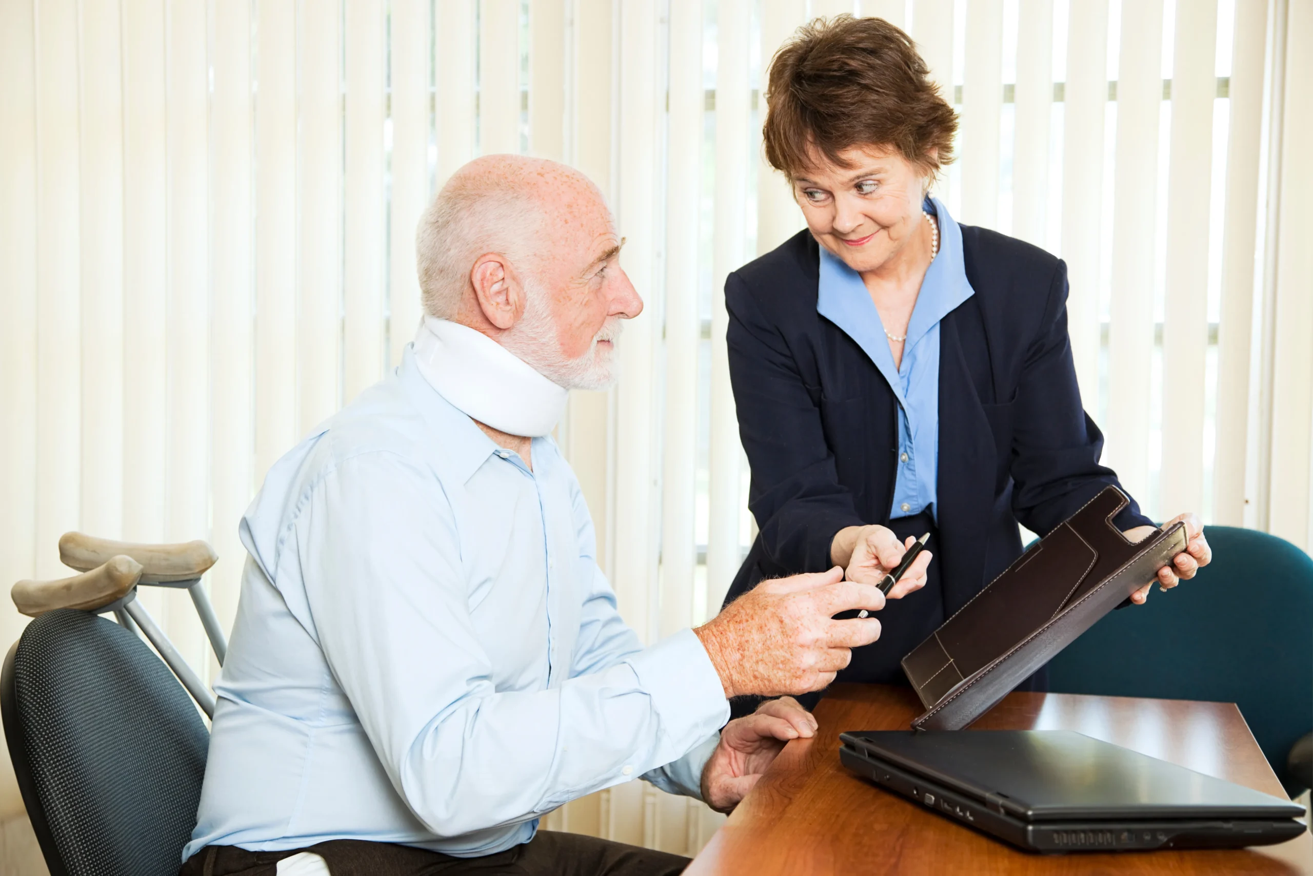 An elderly man wearing a neck brace, signing documents at a lawyers office.