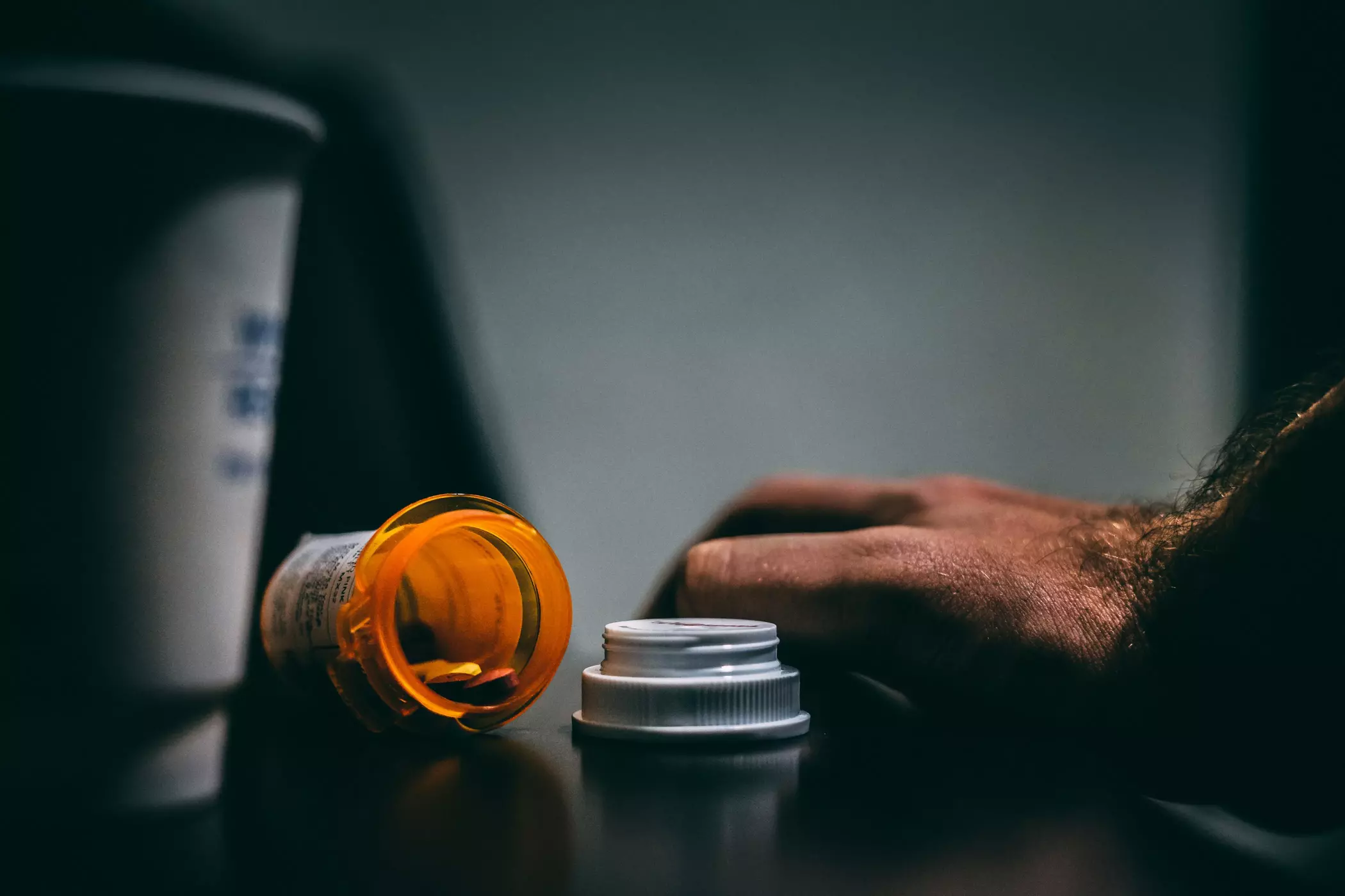 A person holding a pill bottle cap.